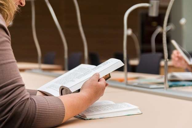 A student going through a book in a library