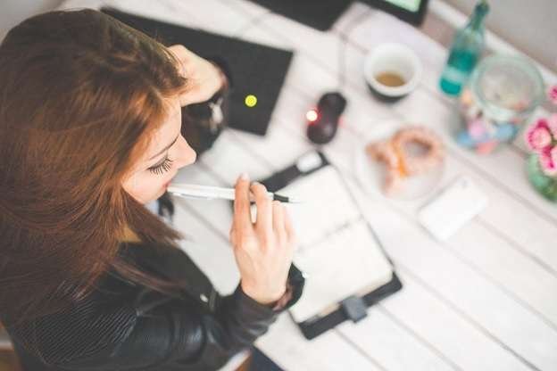 A young woman sitting at a desk and thinking